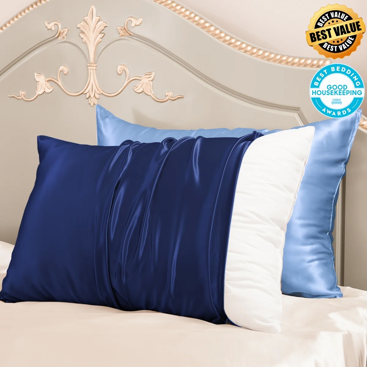 Two mulberry silk pillowcases in navy and light blue draped over a bed with a white ornate headboard